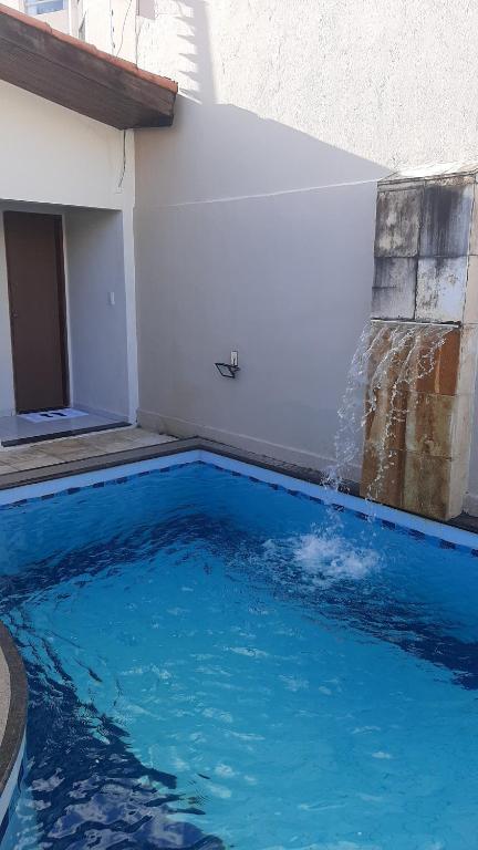 een groot blauw zwembad met een fontein bij Casa em Natal Cond. Fechado com Piscina-03 Suítes in Natal