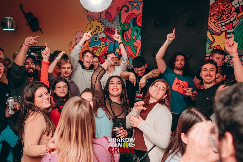 a group of people standing in a room with their hands up at Let's Rock Party Hostel in Kraków