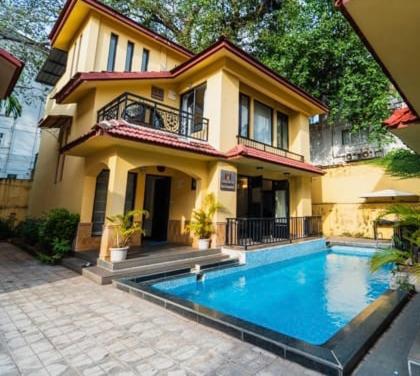 a house with a swimming pool in front of a house at VILLA M - LAGOON 4 CALANGUTE GOA 3BHK, Pool Facing, Near Beach, Free Breakfast, Free WIFI and Well Located in Old Goa