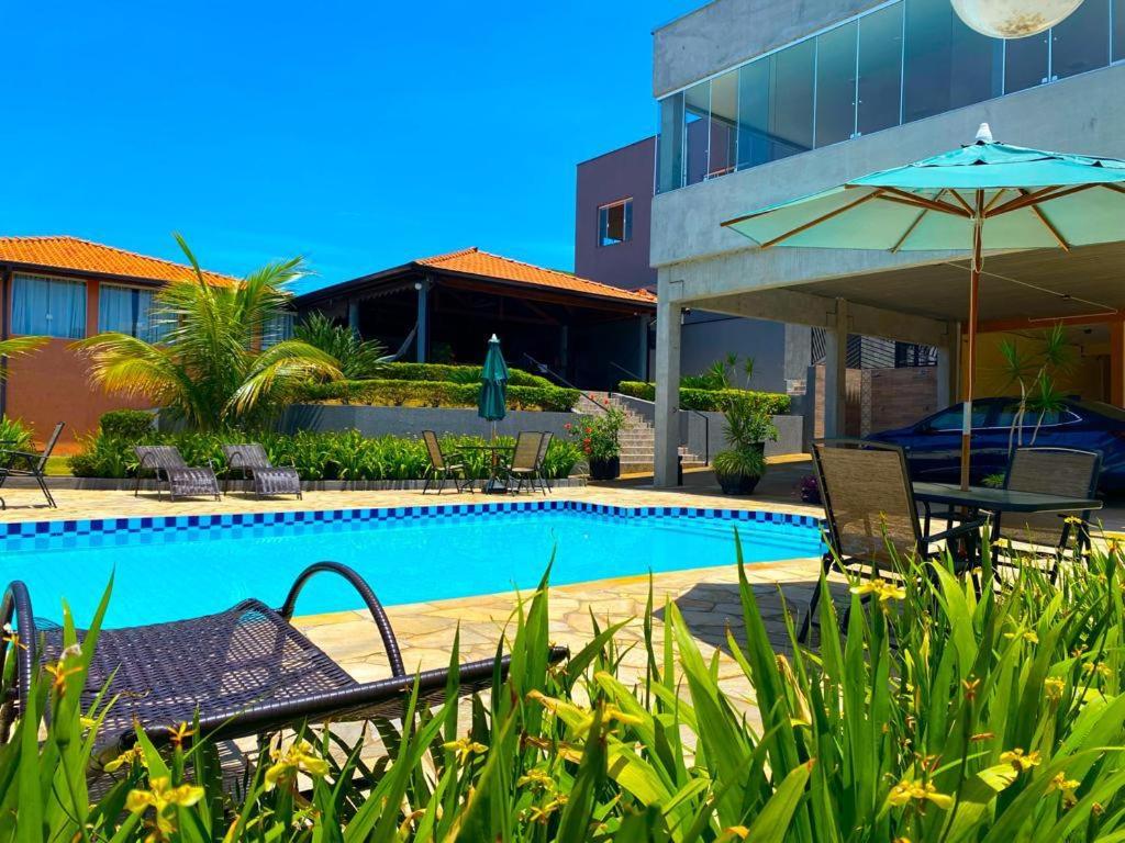 a swimming pool with a table and an umbrella at Hotel Imigrantes in São Pedro