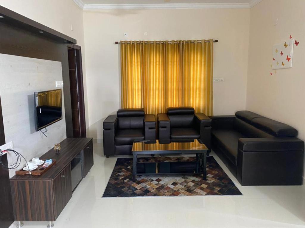 a living room with a black leather couch and a table at OM SRINIVASA - TRULY HOMESTAY in Tirupati