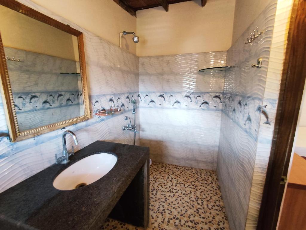 een badkamer met een wastafel en een spiegel bij Maria Paulo Guest House Bar and Restaurant in Agonda