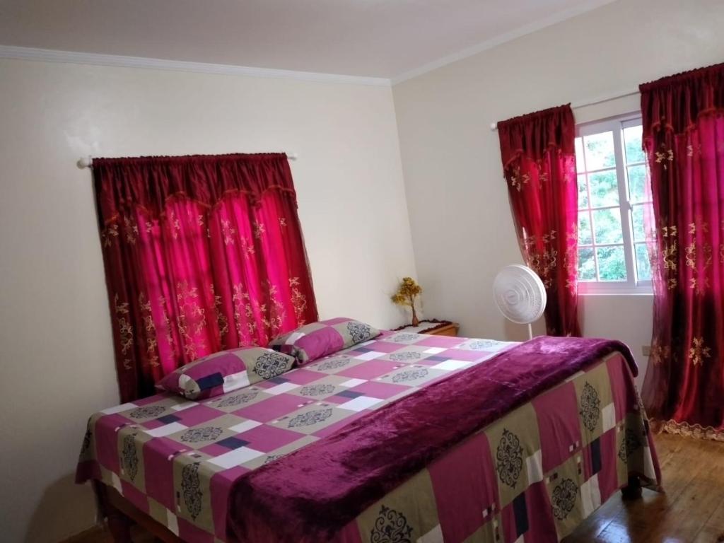 a bedroom with a purple bed with red curtains at Jay's Guest House II in Epping Farm