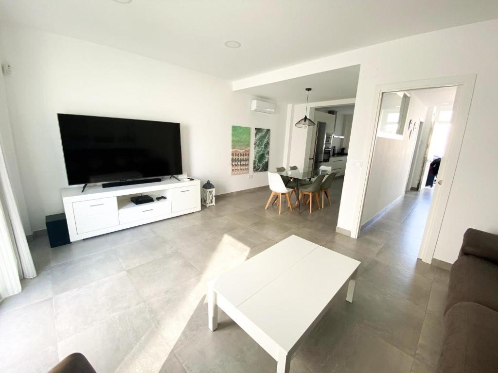 een woonkamer met een grote flatscreen-tv bij Casa moderna, piscina, playa, TV75, Netflix, PS4 in Conil de la Frontera