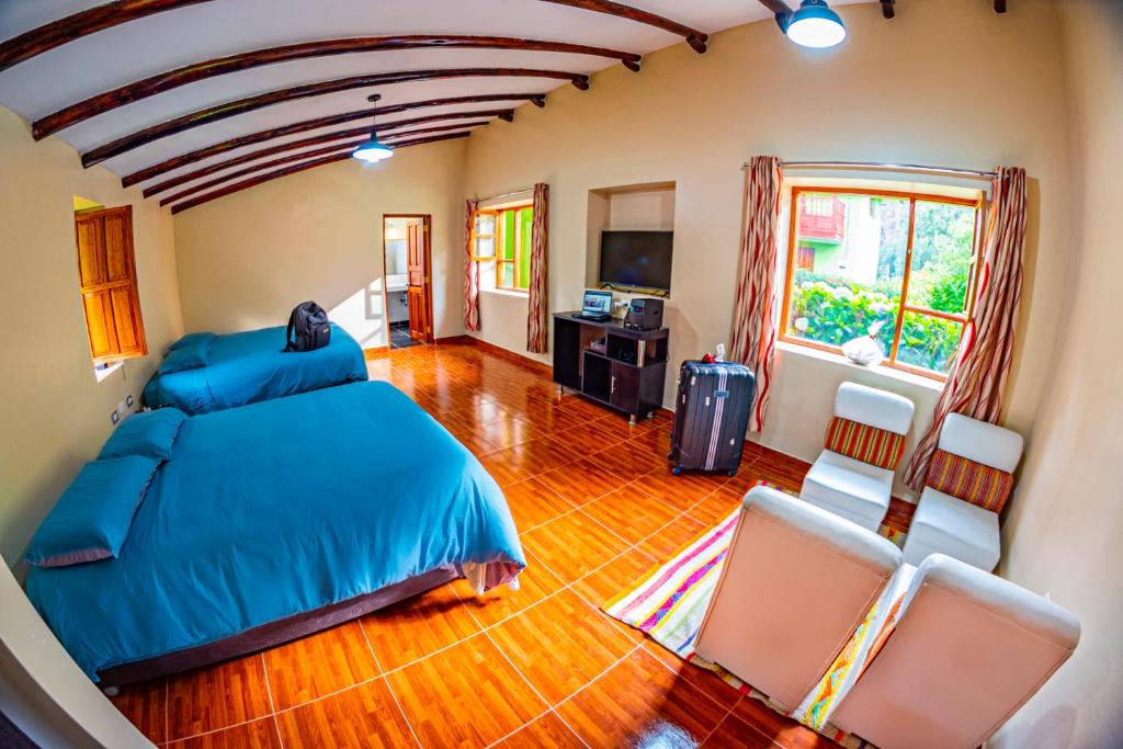 a bedroom with a blue bed and two chairs at Happy Land Valle Sagrado in Urubamba