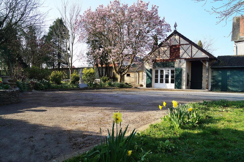 a house with a driveway and flowers in front of it at Normand'Histoire Gite 1869 in Isigny-sur-Mer