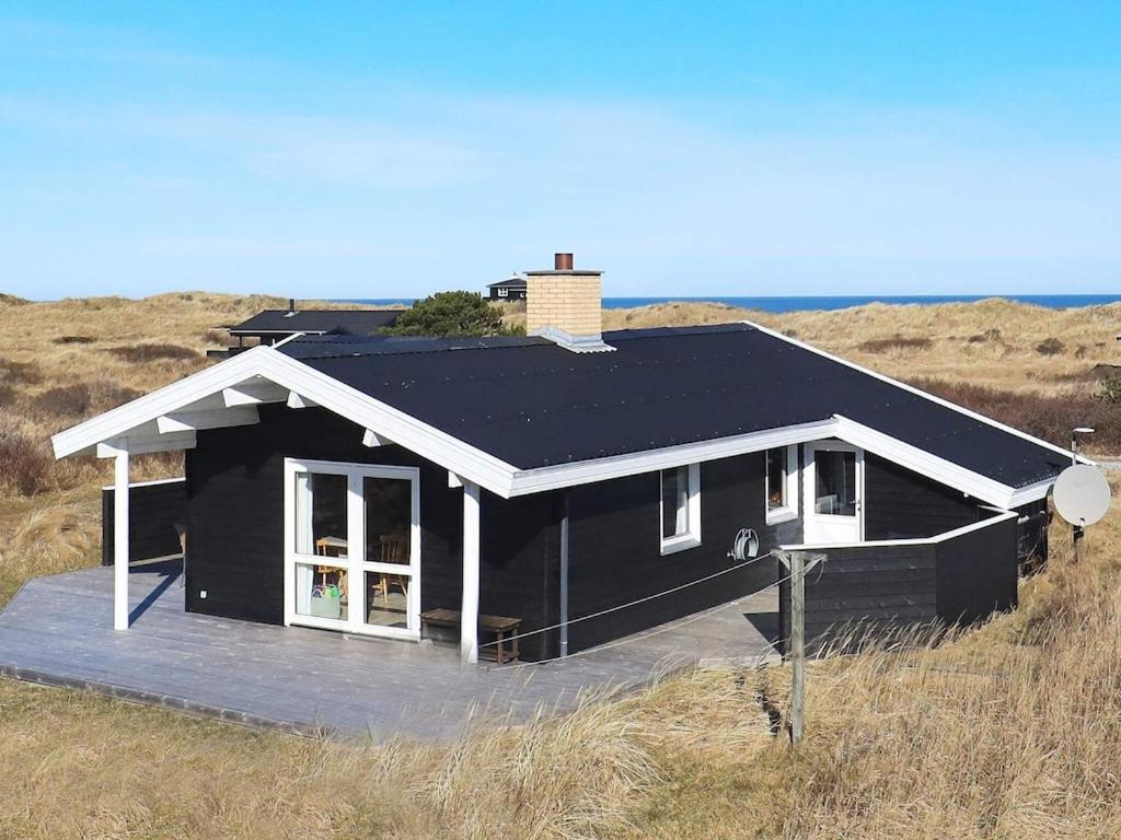a black house in the middle of a field at Cozy Beach House in Kjul - By Traum Ferienwohnungen in Hirtshals