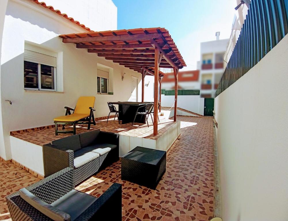 um pátio com uma pérgola, cadeiras e uma mesa em A Casa da Mila - Beach House em Costa da Caparica