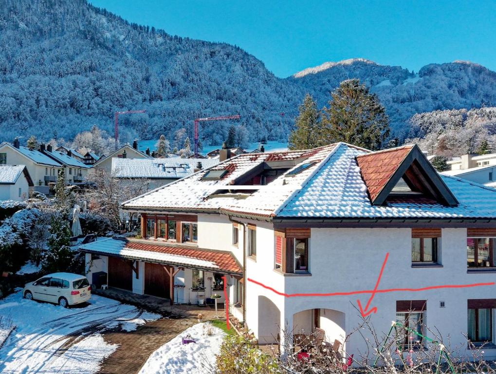 uma casa com telhado de azulejo com montanhas ao fundo em Home, Swiss Home 