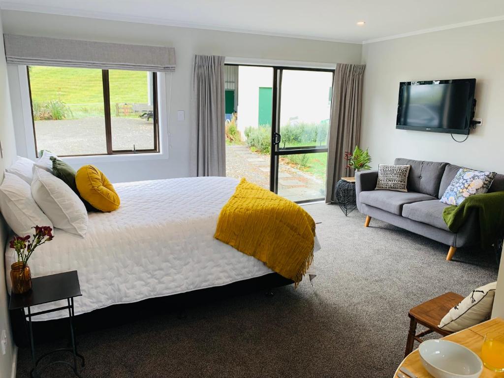 - une chambre avec un grand lit et un canapé dans l'établissement Aranui Farmstay, à Grottes de Waitomo