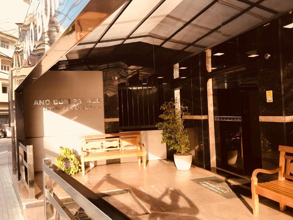 a store front with benches and plants on a building at Ano Bom Palace Hotel in Barra Mansa