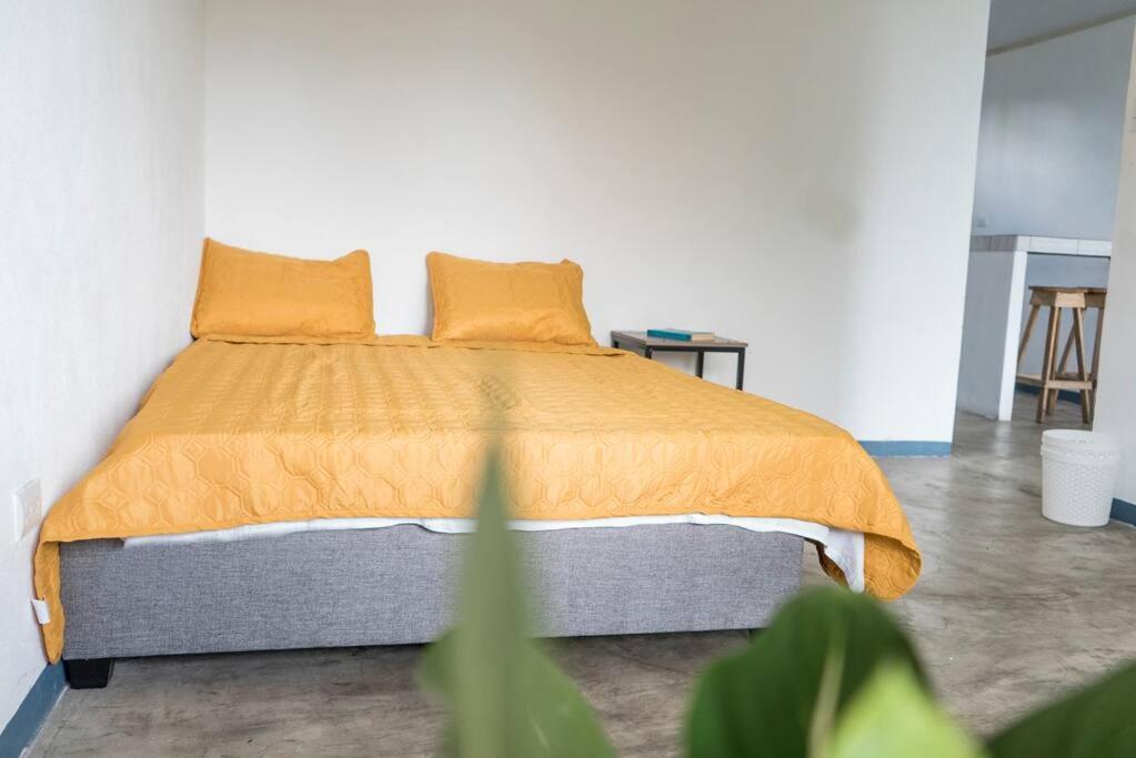 uma cama com um edredão laranja e duas almofadas em NAPPO Room 2 Alajuela, Heredia,SJO,5min from airport NO PARKING em Guácima