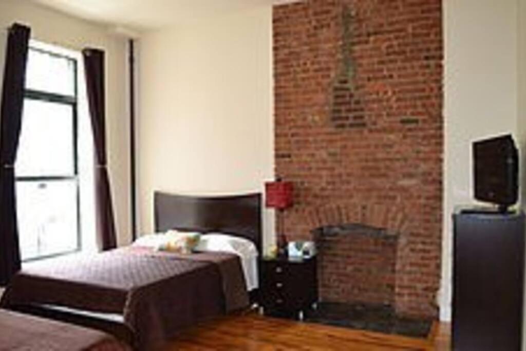 um quarto com uma cama e uma parede de tijolos em 136TH UNIT 1 em Nova York