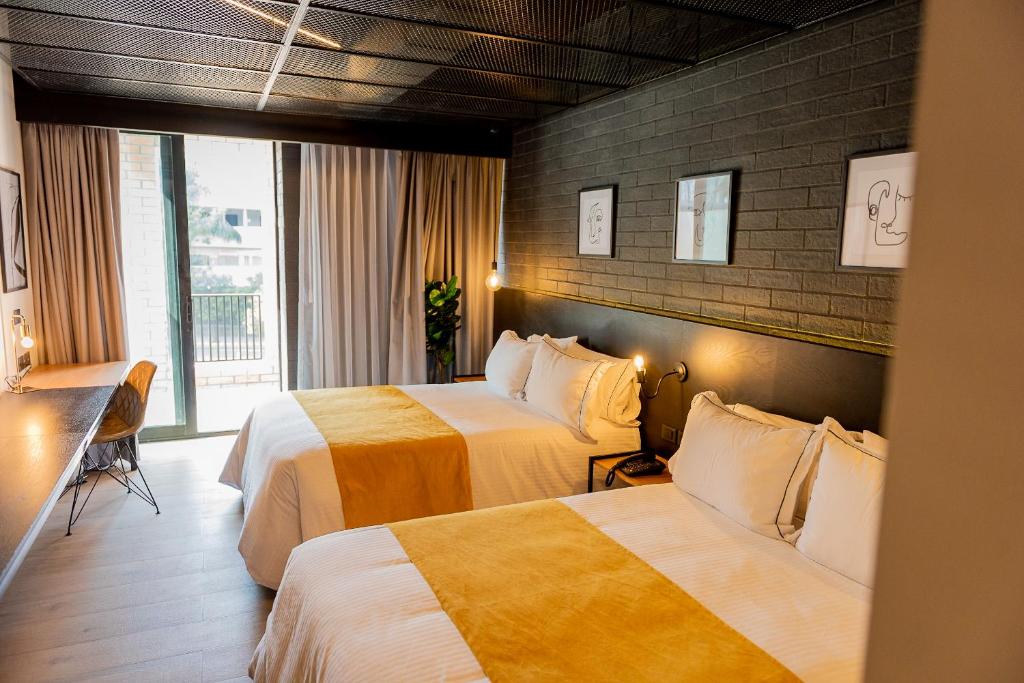 a hotel room with two beds and a window at FULTON Business Luxury HOTEL in Guadalajara