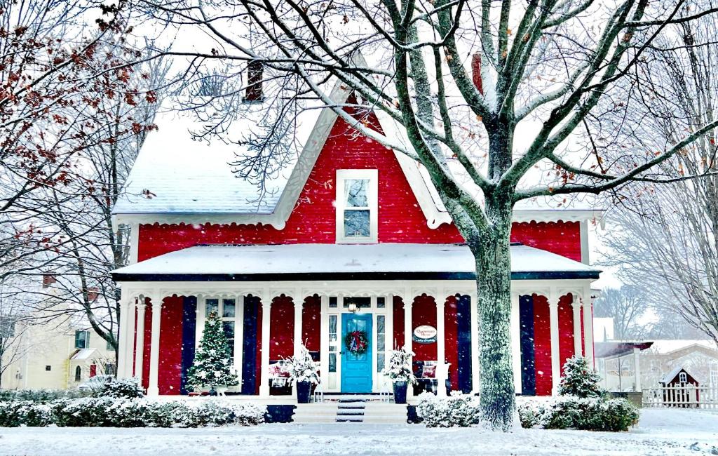 une maison rouge avec une porte bleue dans la neige dans l'établissement Quartermain House Bed & Breakfast, à Fredericton