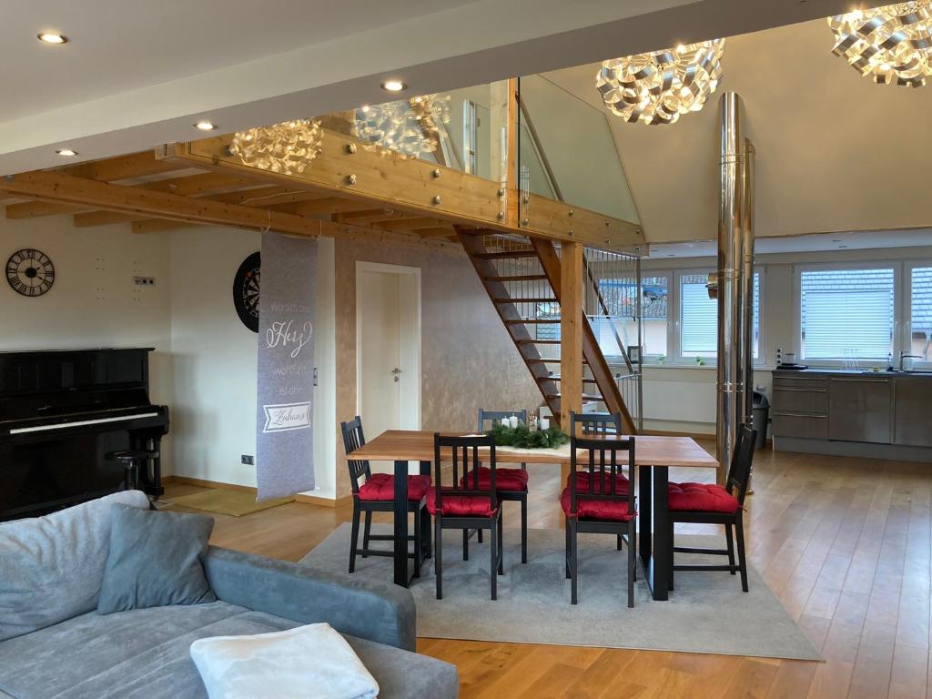 a living room with a table and chairs and a staircase at Saarburg Wine Apartments in Saarburg