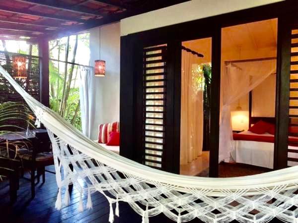 a white hammock in a room with a bedroom at Mangueira Boutique Hotel in Ilha de Boipeba