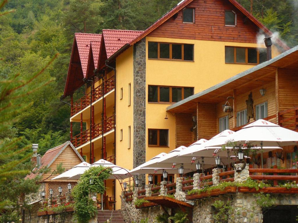 a large building with umbrellas in front of it at Pension Curmatura Stezii in Răşinari