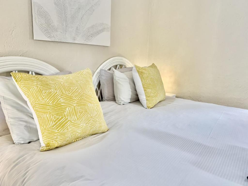 ein weißes Bett mit gelben und weißen Kissen darauf in der Unterkunft Rondebossie Farm Retreat in Magoebaskloof