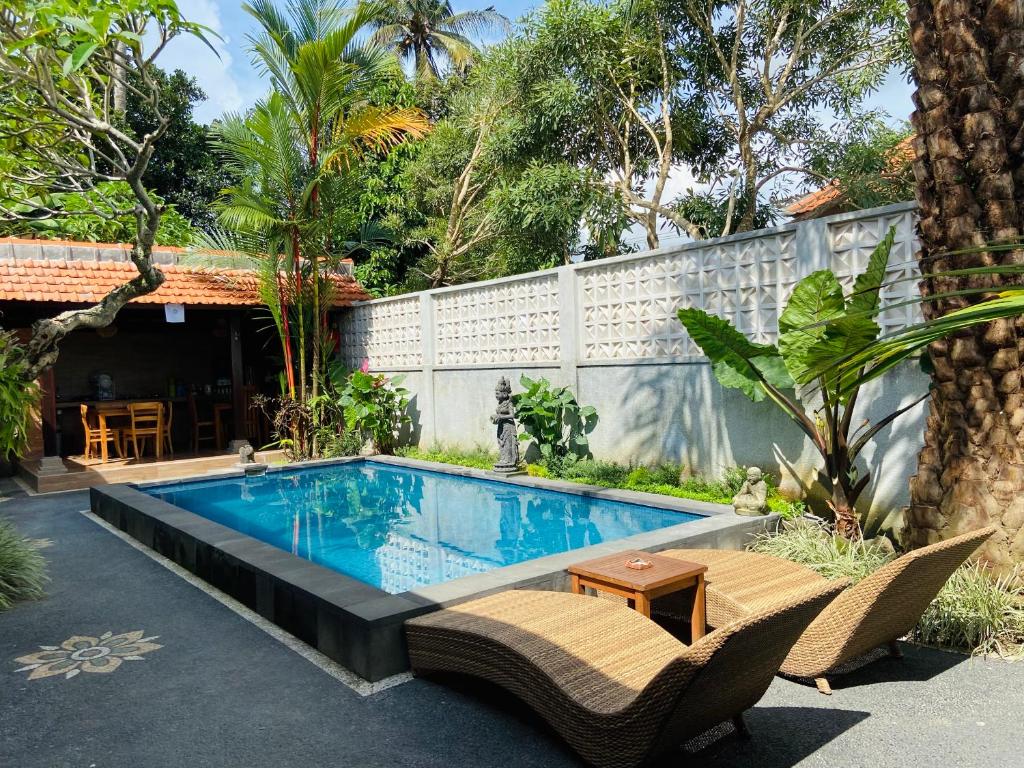 een zwembad in een achtertuin met stoelen en een tafel bij Kanda Villa in Ubud
