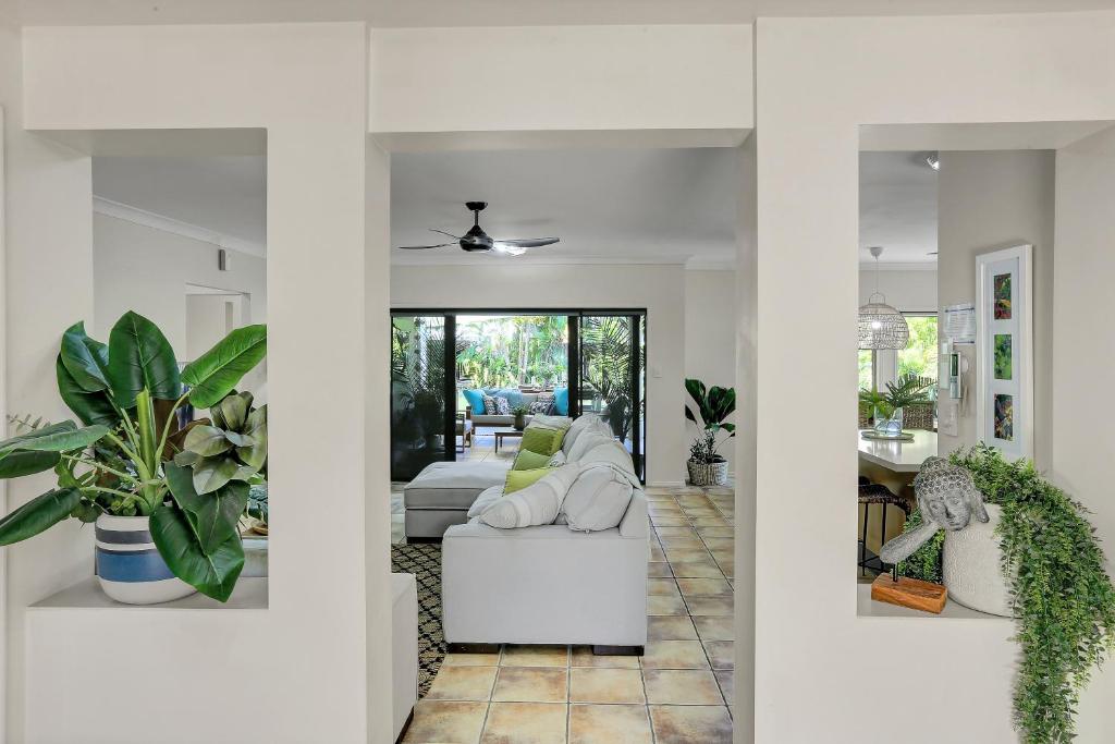 a living room with a white couch and plants at Villa Blue - Coastal Family Escape in Palm Cove