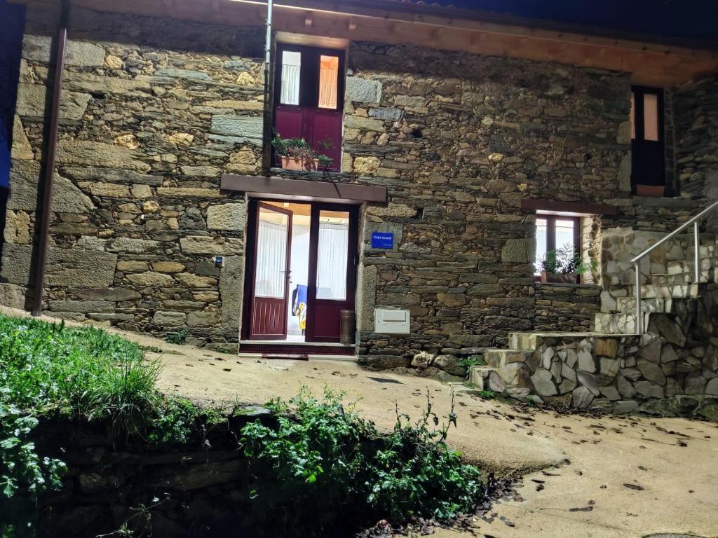 uma casa de pedra com uma porta roxa e janelas em Casa Doade, en A Ribeira Sacra em Doade