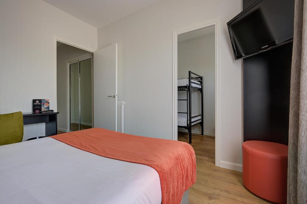 a hotel room with a bed and a tv and a room at Brit Hotel Europ Bergerac in Bergerac