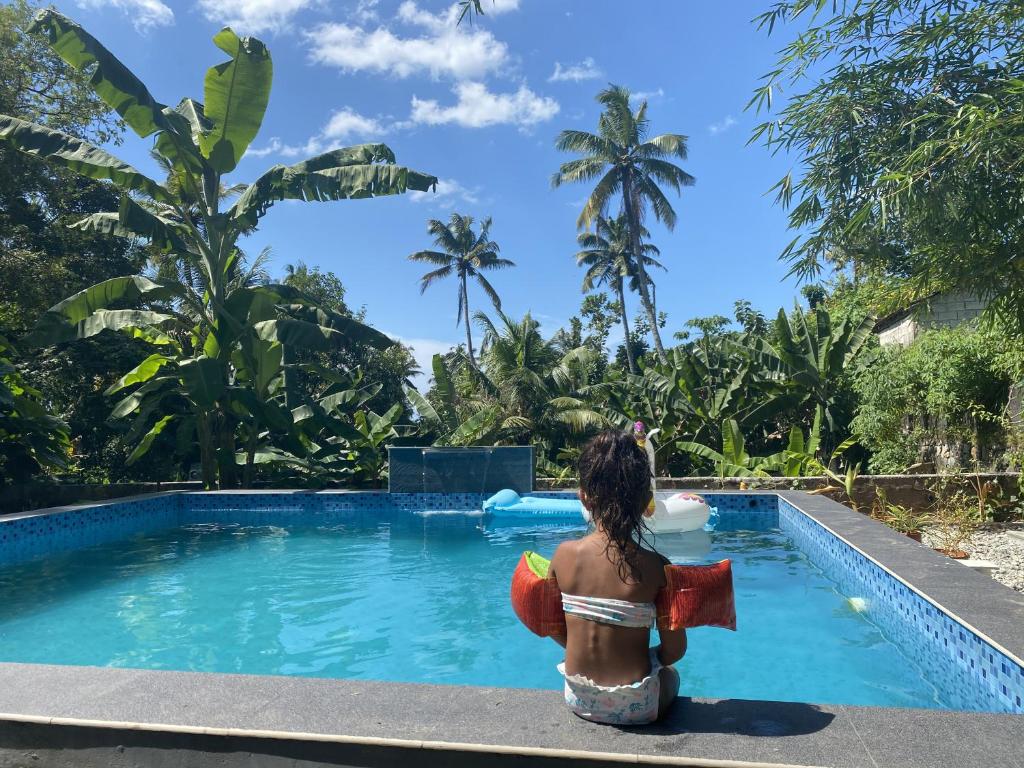 a woman in a bikini sitting next to a swimming pool at Tamarind Villa in Varkala