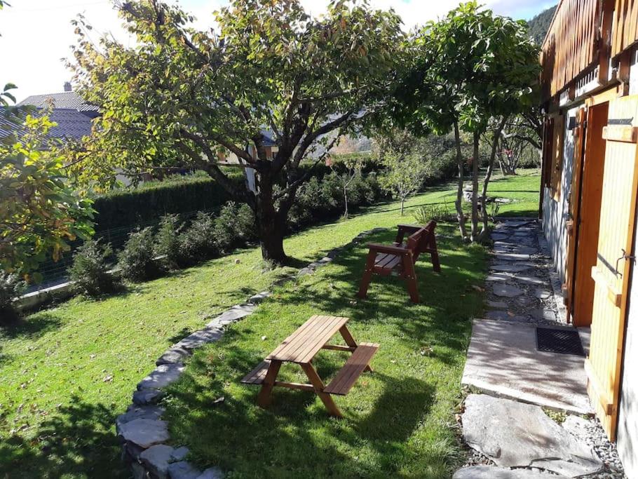 a garden with two wooden benches in the grass at Appartement neuf, une chambre avec parking in Séez