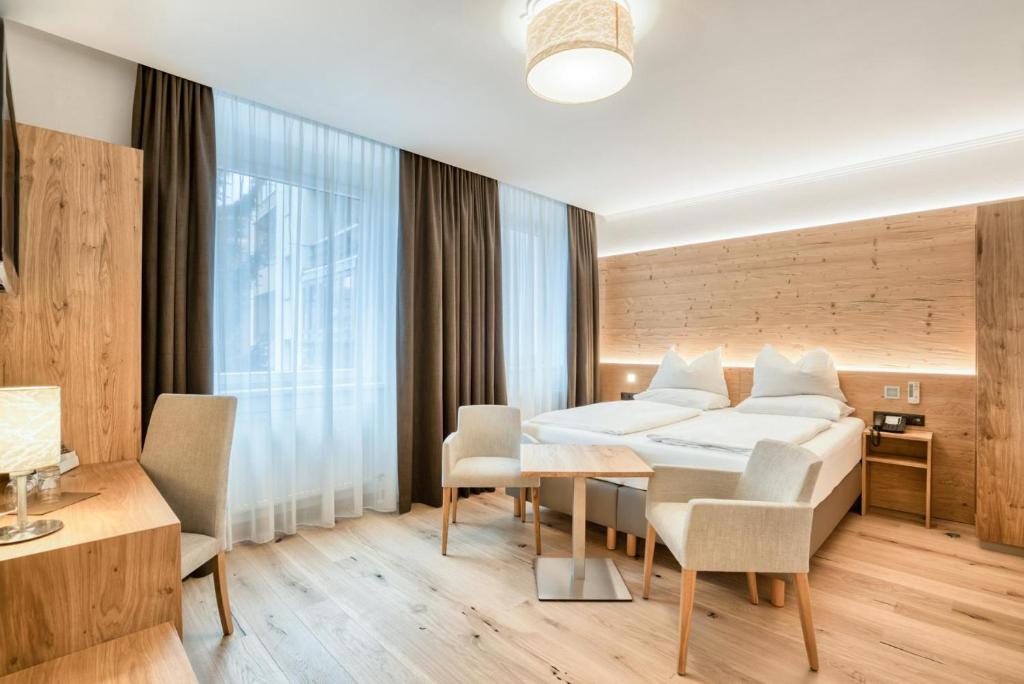 um quarto de hotel com uma cama, uma mesa e cadeiras em Leipziger Hof Innsbruck em Innsbruck