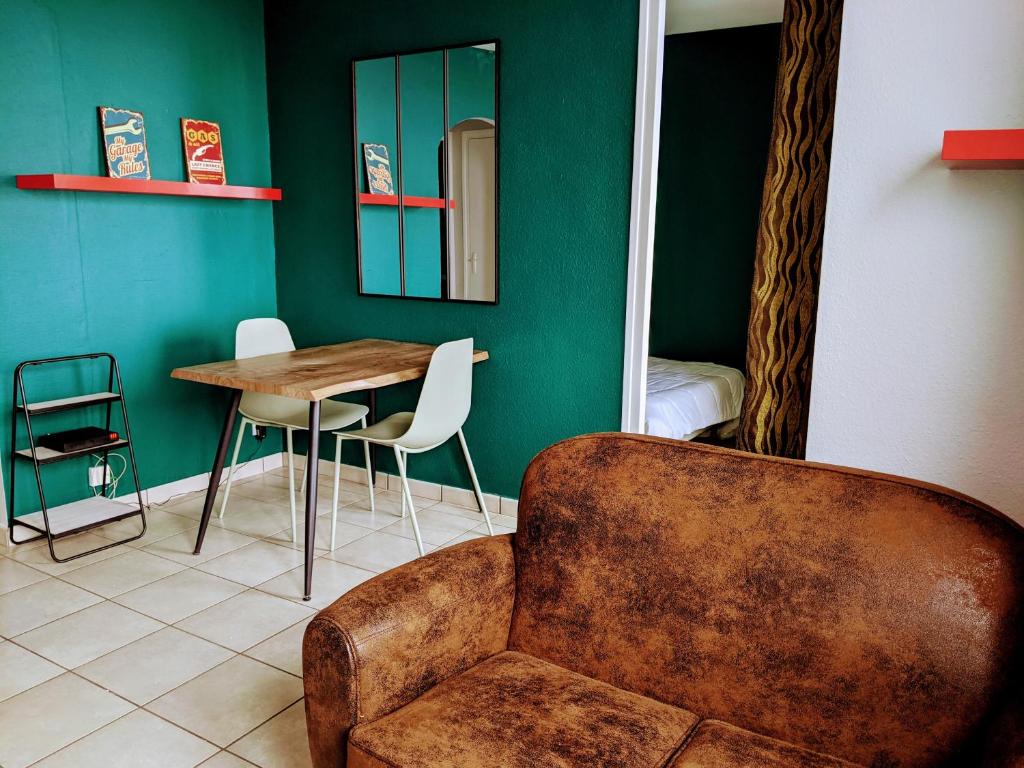 - un salon avec un canapé, une table et une chaise dans l'établissement Saint-Etienne Appart'hôtel de Bellevue, à Saint-Étienne