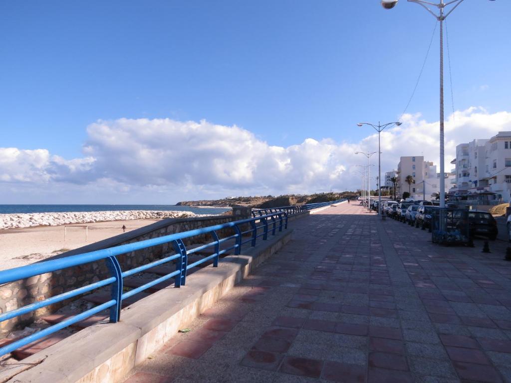 a sidewalk next to a beach with a blue railing at Beautiful appartment with a glorious sea view in Monastir