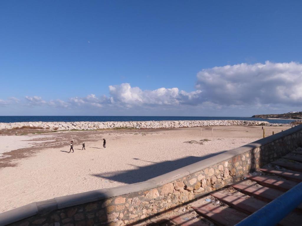 two people walking on a beach near the ocean at Beautiful appartment with a glorious sea view in Monastir