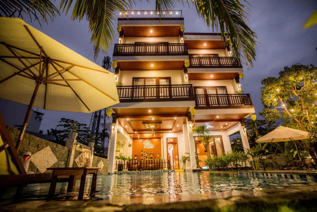 a house with a swimming pool and an umbrella at SenDa Villa & Apartment Hoi An in Hoi An