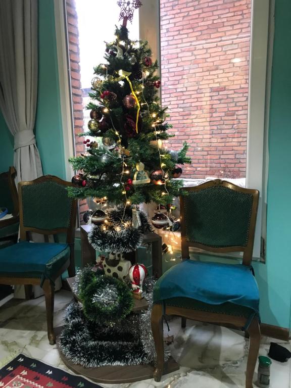a christmas tree in a room with two chairs at Griboedov 13 in Tbilisi City