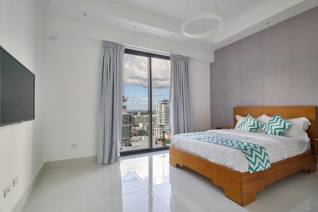 - une chambre avec un lit et une grande fenêtre dans l'établissement Monaco Residences Piantini, à Saint-Domingue