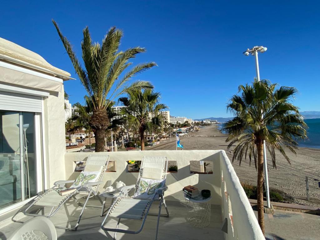 un balcón con sillas, palmeras y la playa en Puerto, en Benalmádena