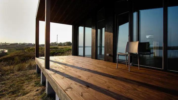 a wooden deck with a chair on the side of a house at Villa Beykush in Blizhniy Beykush