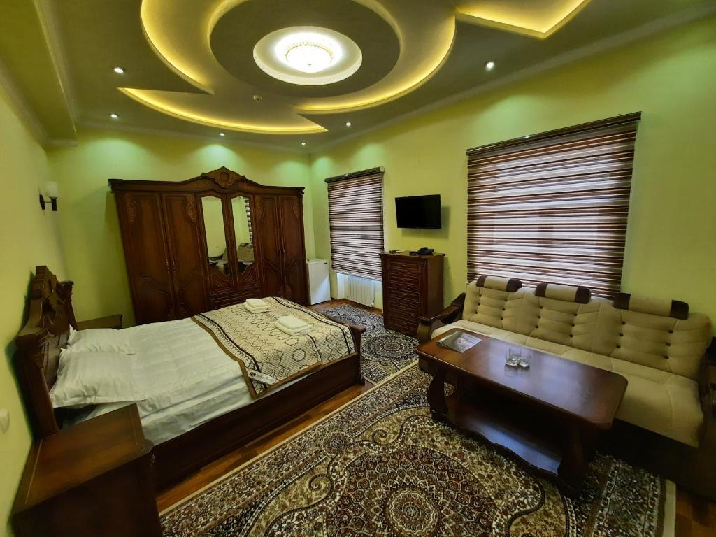 a bedroom with a bed and a couch and a ceiling at VOSTOK in Samarkand