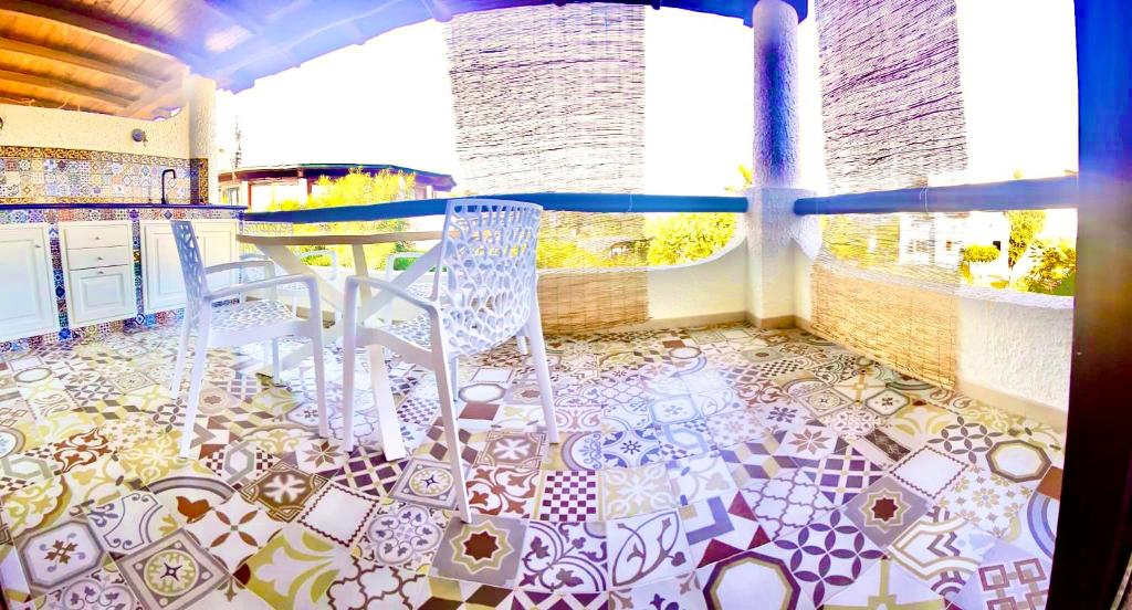 balcón con 2 sillas y mesa en el suelo de baldosa en Apartment Suite residence al porto Vulcano, en Vulcano
