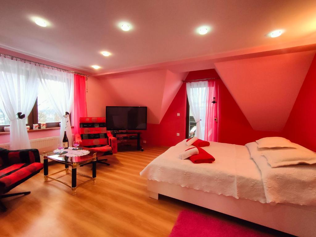 a bedroom with red walls and a bed and a tv at Bajeczny Wypoczynek Apartamenty in Witów