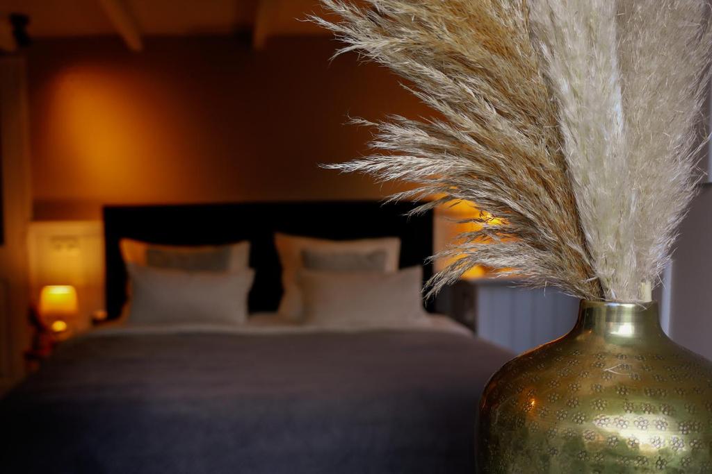 a vase filled with feathers sitting next to a bed at B&B Mañana in Cuijk