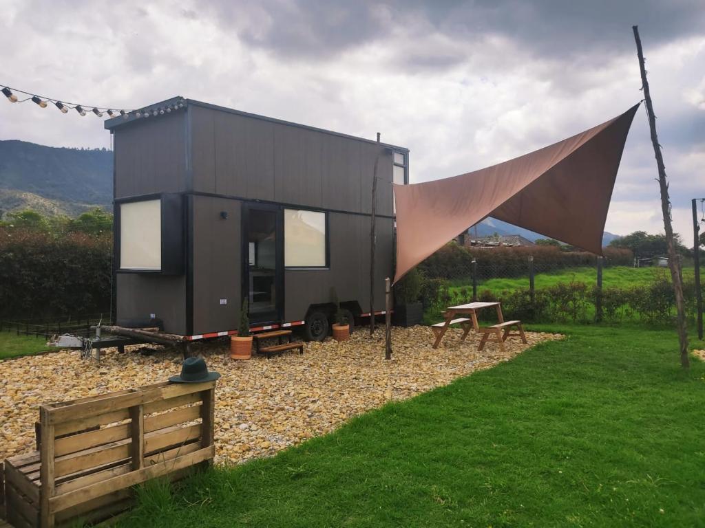 a black tiny house with a tent in a field at Quyé Tiny House in Tenjo