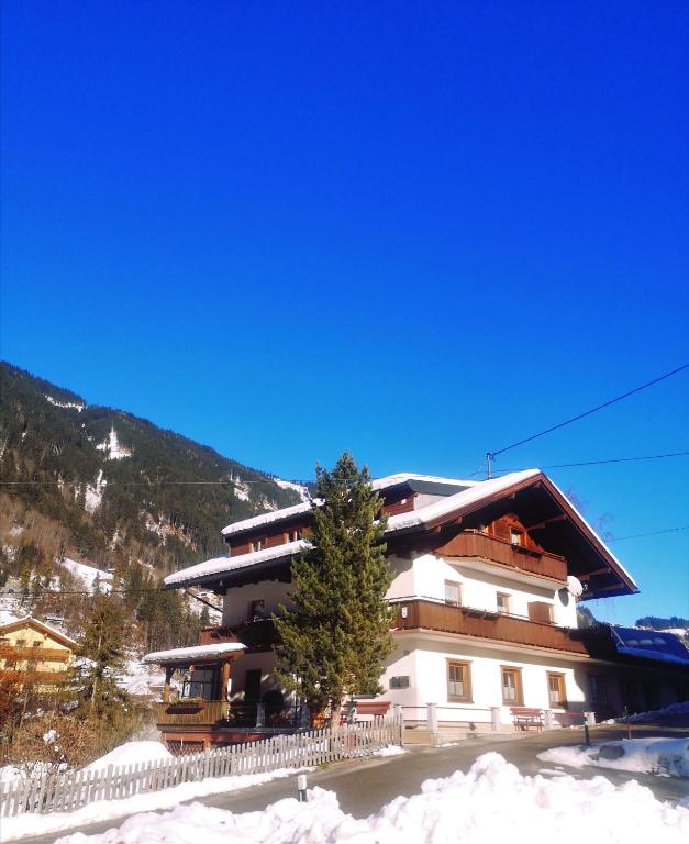 a large building with a tree in the snow at Haus Grünberg in Finkenberg