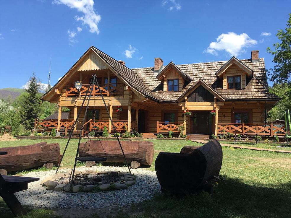 a large log cabin with a fire pit in front of it at Biesówka in Wetlina
