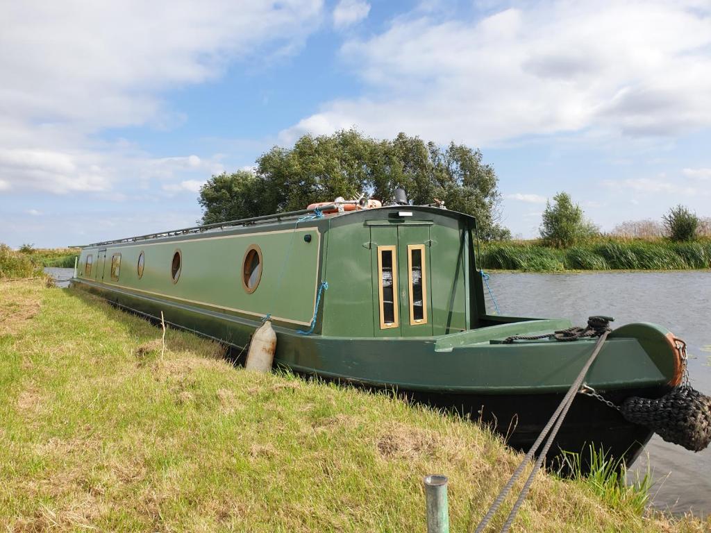 een groene boot geparkeerd aan de kant van een rivier bij Cambridge Boat Hire in Chesterton