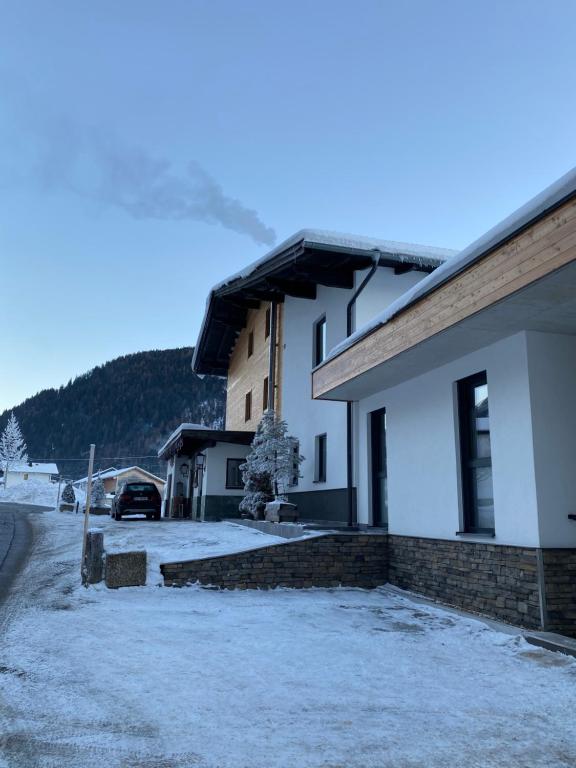 une maison avec de la neige devant elle dans l'établissement Pension Bucher, à Schnann