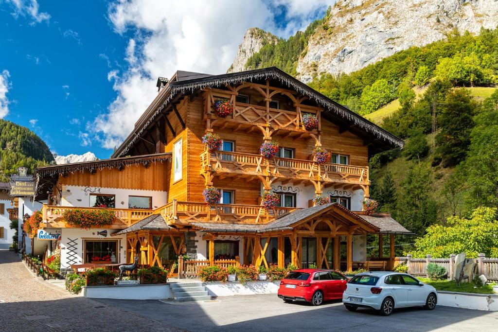 una gran casa de madera con coches aparcados frente a ella en Alpenhotel La Montanara, en Rocca Pietore