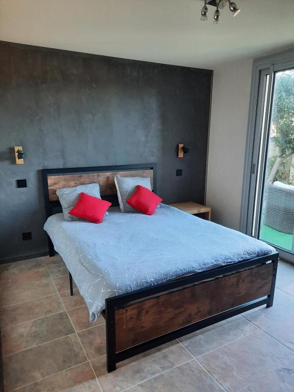 ein Schlafzimmer mit einem Bett mit zwei roten Kissen in der Unterkunft Rêves de vie Studio Morgiou avec terrasse et parking privé in Cassis