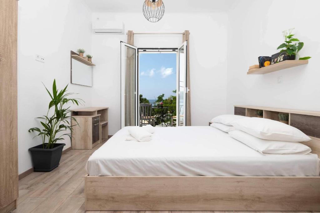 ein weißes Schlafzimmer mit einem Bett und einem Fenster in der Unterkunft Giorgos' House Gialova in Gialova